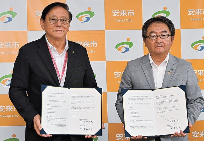 協定書を手にする生協しまねの安井光夫理事長（右）と田中武夫安来市長＝安来市安来町、市役所安来庁舎