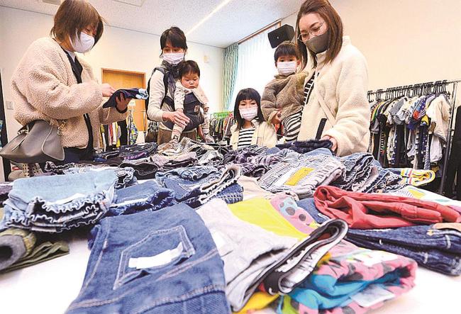 リユースコーナーで子供服を選ぶ親子連れ＝島根県西ノ島町浦郷、コミュニティ図書館いかあ屋