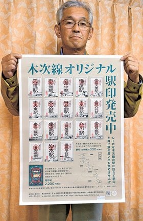 木次線全１８駅の「駅印」を載せたポスターを持ち、ＰＲする和久利健さん＝島根県奥出雲町内