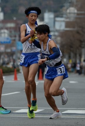 平田の６区冨岡成望（左）からたすきを受け、走り出す７区加藤蒼梧＝西大路下立売、第６中継所