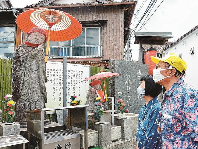 紅白模様に貼り替えられた淀江傘の下に立つ咲い地蔵（左端）＝米子市東倉吉町