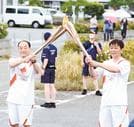 次の走者に聖火を引き継ぐ斎藤博之さん（左）＝浜田市原井町