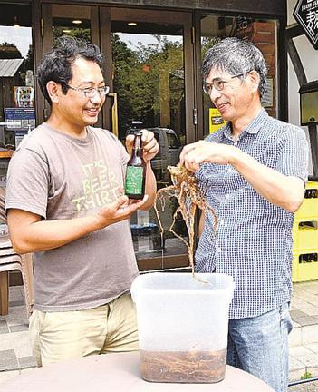 発売するサワービールを手にする石見麦酒の山口厳雄工場長（左）と、石州勝地半紙の佐々木誠代表＝江津市桜江町長谷、石見麦酒