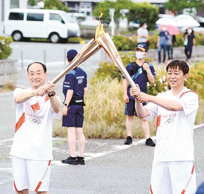 次の走者に聖火を引き継ぐ斎藤博之さん（左）＝浜田市原井町