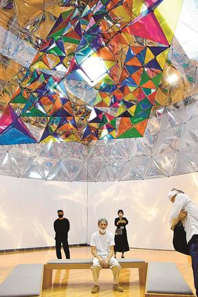 天井からつるされた自身の作品を紹介する野村康生さん（中央）＝益田市有明町、島根県立石見美術館
