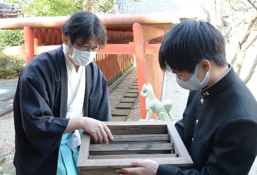 制作したさい銭箱を花田英己宮司(左)に手渡す佐藤龍之介さん=出雲市上塩冶町、塩冶神社