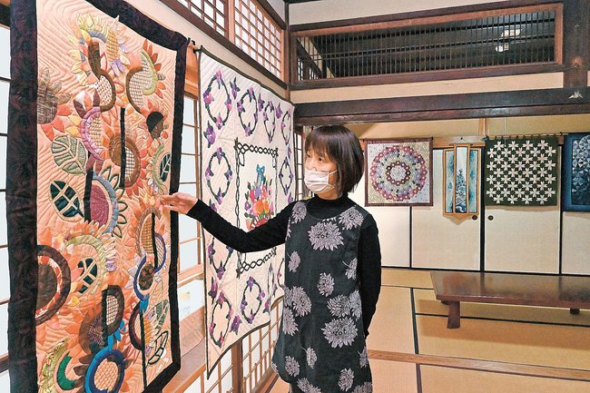 色とりどりのタペストリー作品を紹介する布澄会のメンバー＝出雲市斐川町原鹿、旧豪農屋敷
