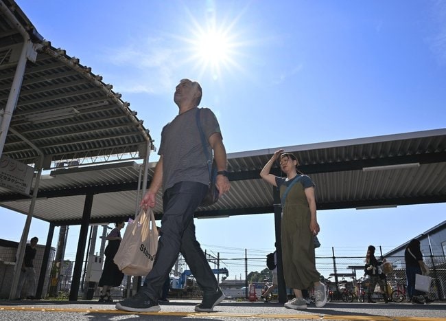気温４０度に迫る猛暑日となった三重県桑名市内を歩く人たち＝２日午後