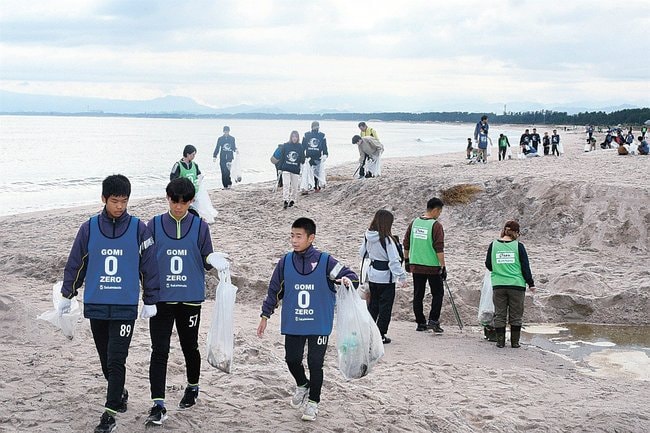 弓ケ浜でごみを拾い集める参加者=境港市新屋町付近