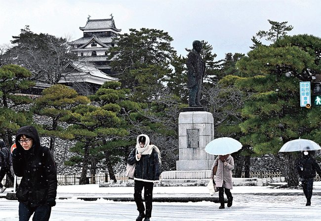 雪が降る中、足早に歩く人々＝１０日午前８時２０分、松江市殿町