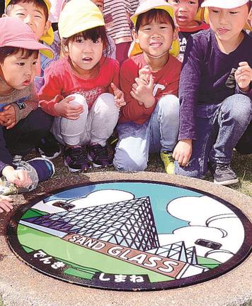 地元保育園児を前にお披露目されたマンホール＝大田市仁摩町天河内、仁摩サンドミュージアム