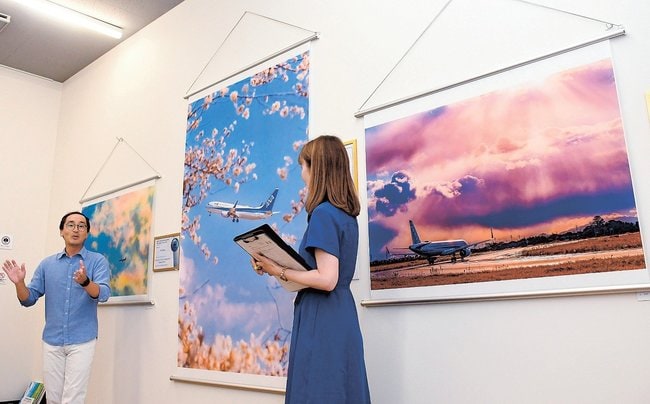 ギャラリートークで飛行機撮影のポイントを解説する宮川大志さん(左)=倉吉市宮川町2丁目、山陰ハウジングプラザ倉吉中央店