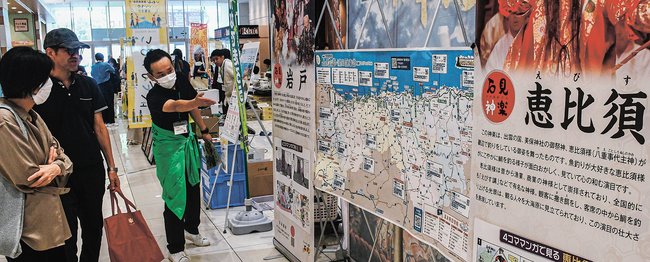 石見地域の観光情報に聞き入る来店客（左）＝広島市安佐南区、イオンモール広島祇園