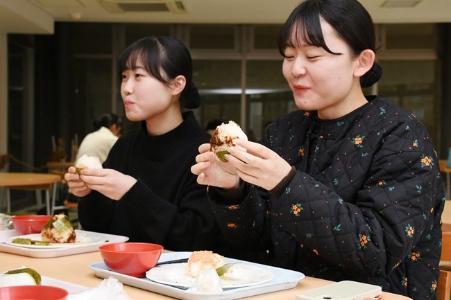 自分で作ったおにぎりを味わう学生＝出雲市西林木町、県立大出雲キャンパス