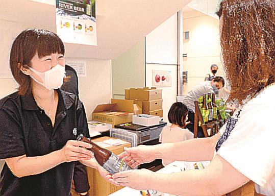 客に地ビールを手渡す上床絵理社長（左）＝松江市朝日町、シャミネ松江