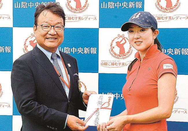 ９番ホールでホールインワンを達成し、松尾倫男大会会長（左）から賞金を受け取る佐藤絵美＝大山平原ゴルフクラブ