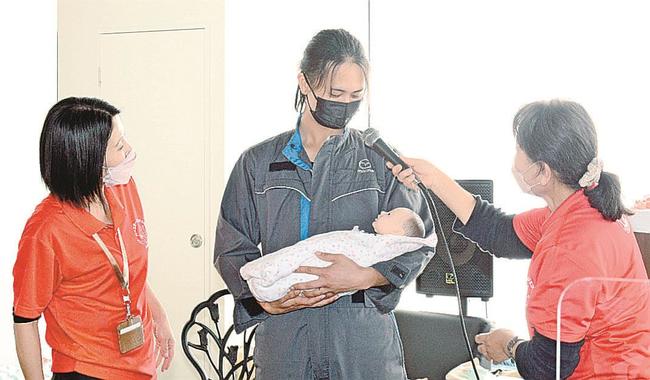 首が据わる前の赤ちゃんを模した人形を抱く社員＝松江市西尾町、マツダオートザム松江