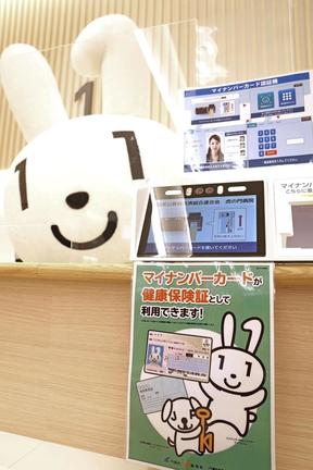 健康保険証の代わりにマイナンバーカードを利用するための読み取り機とＰＲキャラクターのマイナちゃん＝２０２１年１０月、東京都内