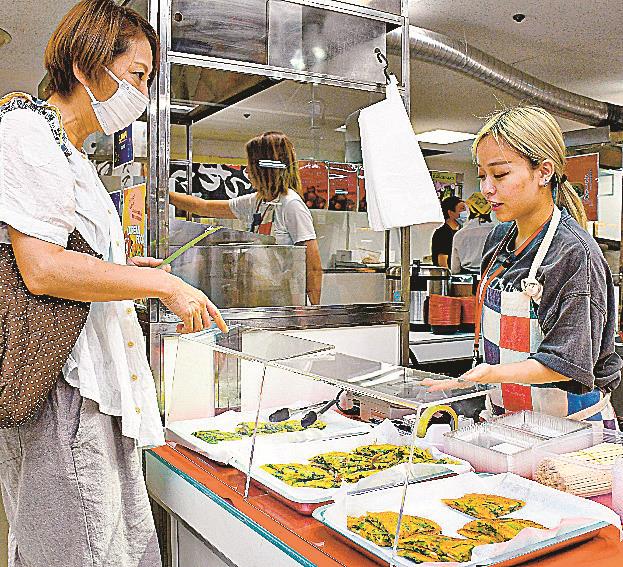 来場者(左）に焼きたてのチヂミを販売する売場担当者=米子市角盤町１丁目、ＪＵ米子高島屋