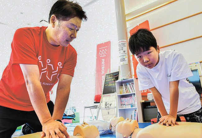 小学生に心臓マッサージの方法を伝える狩野祐次代表（左）＝松江市黒田町、トヨタカローラ島根黒田店
