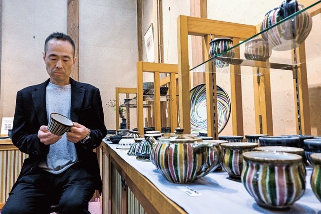 鮮やかな色使いの作品を見る河井一喜さん＝松江市末次本町、くらしの器森脇