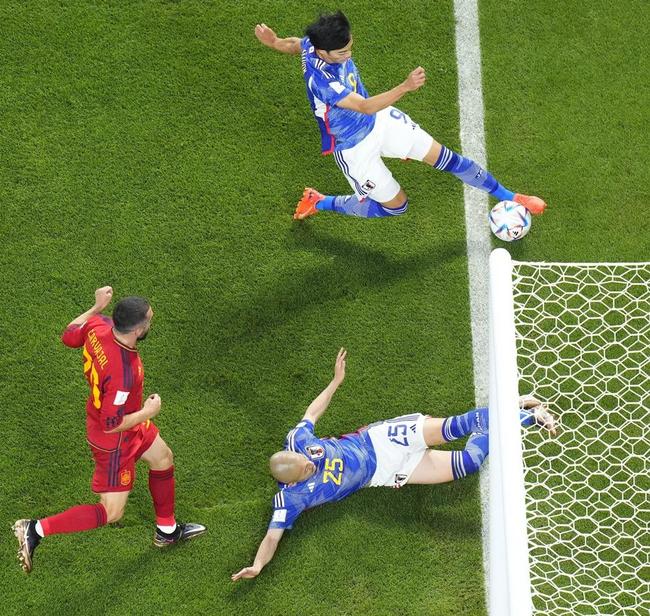 サッカーワールドカップのスペイン戦後半、ゴールライン際のボールを折り返す日本代表の三笘薫選手（上）。これが決勝ゴールにつながった＝２０２２年１２月２日、ドーハ（ＡＰ＝共同）