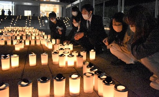 キャンドルを見つめ丸１３年を迎えた事件の被害者を追悼する学生ら＝浜田市野原町、県立大浜田キャンパス