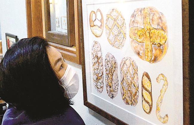 パンを精緻に描いた作品を眺める来場者＝大田市大森町、ギャラリーひまわり館