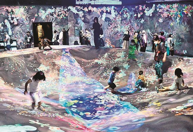 壁や床に投映されたデジタルアートを追いかけ、手で触れて遊ぶ子どもたち＝松江市袖師町、島根県立美術館