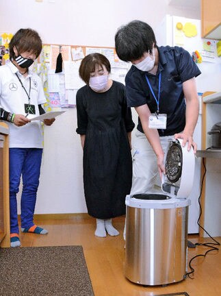 家庭に実証実験用の生ごみ処理機を設置する隠岐の島町職員(右)=島根県隠岐の島町原田