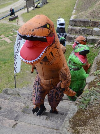 恐竜になりきり月山富田城跡を登る参加者＝安来市広瀬町富田