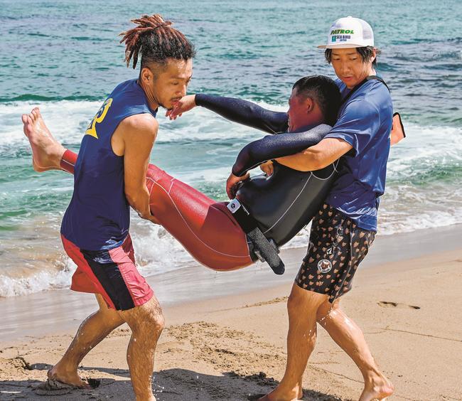 救助訓練で溺れた海水浴客を砂浜に運ぶ参加者＝浜田市国分町、石見海浜公園