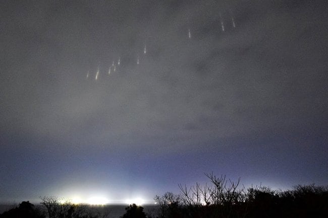 水平線上にともるいさり火の上空に現れた光柱＝２日夜、島根県隠岐の島町岬町（白石泰志さん撮影）