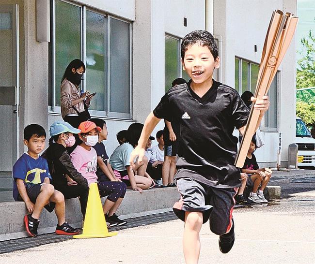 聖火リレーのトーチをバトンにしてリレーする子どもたち＝浜田市黒川町、市東公園