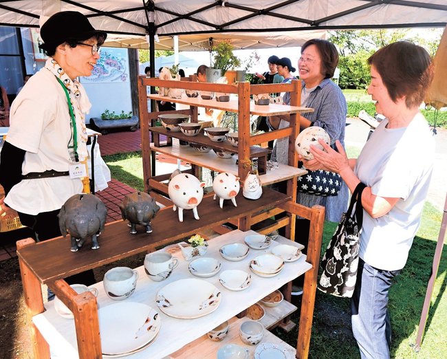 陶芸作家（左）と会話しながら作品を選ぶ来場者＝松江市大庭町、出雲かんべの里