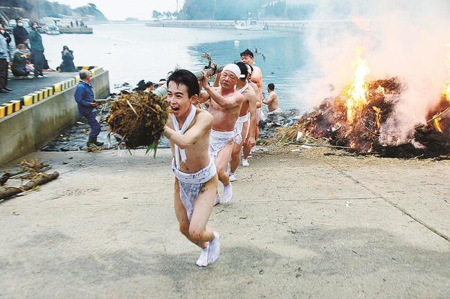 海中から竹を担ぎ出す男衆＝島根県隠岐の島町今津