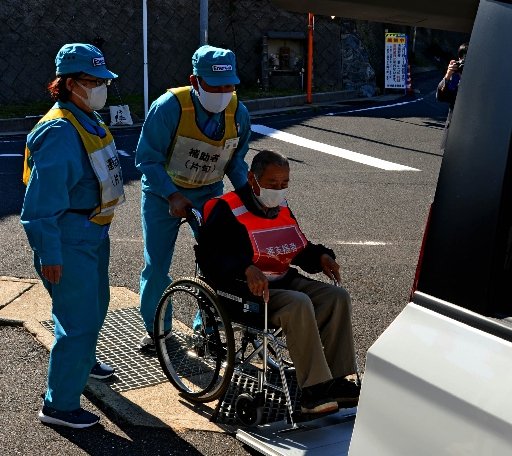 中国電力社員によって車椅子対応の福祉車両に誘導される片句地区の住民＝松江市鹿島町片句