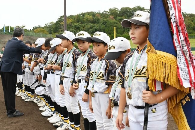 初優勝を果たし、閉会式で優勝メダルを首から下げるKidsベースボールクラブの選手たち=松江市上乃木10丁目、市営野球場