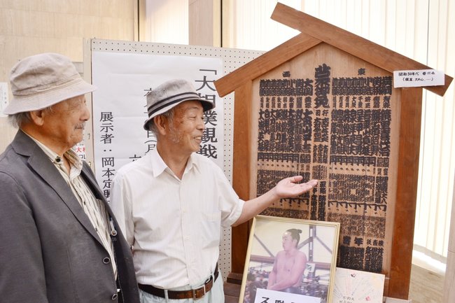 昭和３０年代の木製の番付表を紹介する梶原弘美さん（右）と岡本定興さん＝浜田市殿町、日本海信用金庫本店