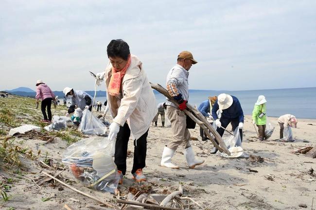 海岸に漂着したごみを拾い集める人たち＝５月30日、出雲市外園町
