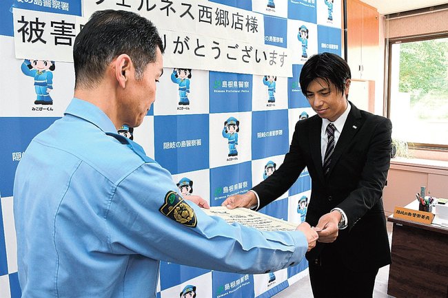 平塚信一署長（左）から感謝状を受け取る板持優悟店長＝島根県隠岐の島町西町、隠岐の島署