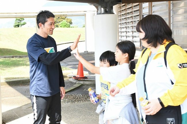 玉田圭司さん（左）とハイタッチしてスタートする参加者＝出雲市矢野町、出雲ドーム
