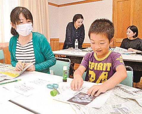 好きな記事を切り取りスクラップに取り組む親子=出雲市斐川町出西、斐川環境学習センター