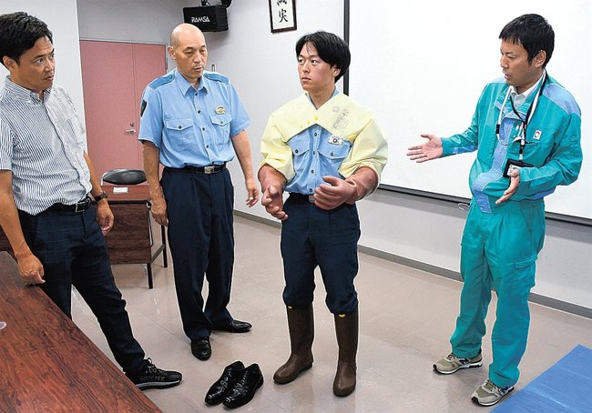 絶縁服と手袋を試着する署員（右から２人目）＝島根県隠岐の島町西町、隠岐の島署