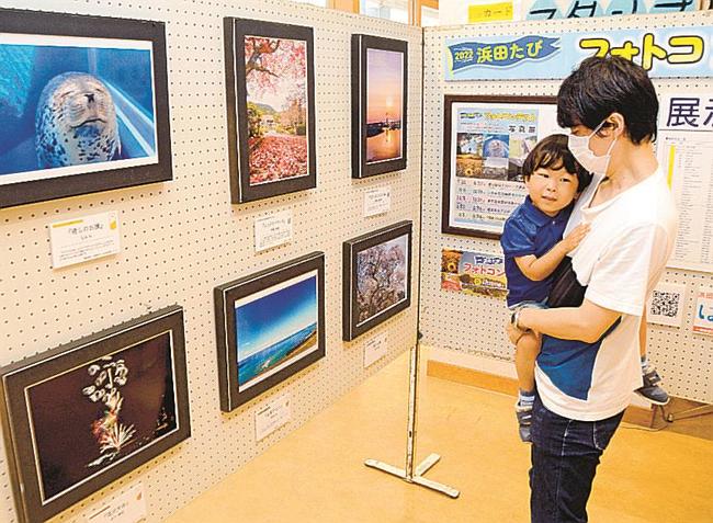 美しい景色を撮影した作品を眺める来場者＝浜田市原井町、道の駅ゆうひパーク浜田