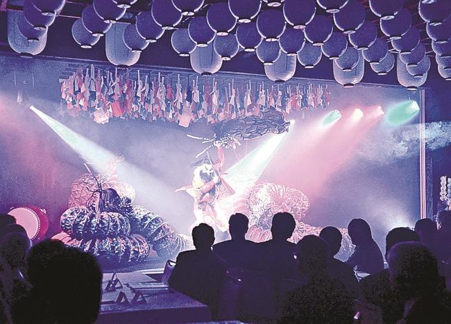 舞乃座で華やかなスポットライトを受け、大蛇を上演する地元の神楽団体