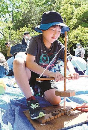 火きりきねを使って火おこしを体験する来場者＝出雲市斐川町神庭、荒神谷史跡公園