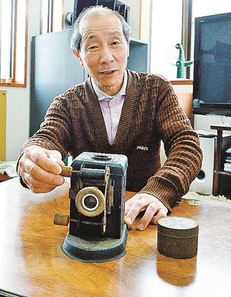 幻灯機を手に雷電を主人公にした漫画について語る上嶋勝己さん＝鳥取市吉成