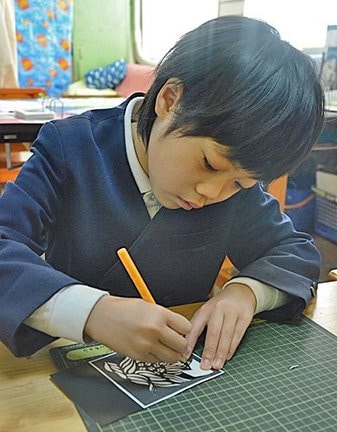 切り絵を制作する勝部旬一郎君＝安来市荒島町、荒島小学校