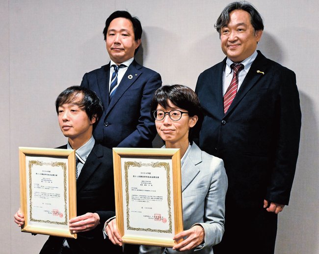 関係者と記念撮影する島根大医学部の大原浩貴講師（前列左）と藤田幸教授（同右）＝松江市朝日町、大和証券松江支店